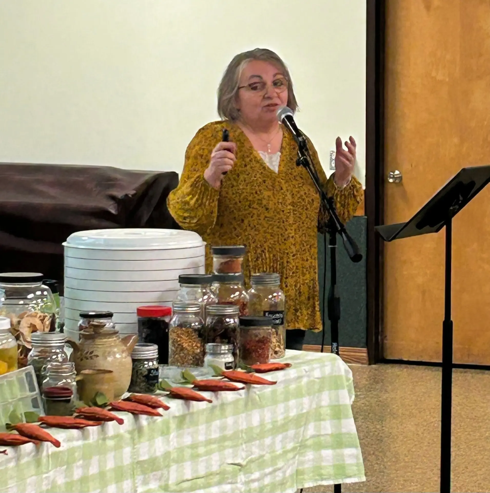 Cindy teaching a dehydrating class with a food dehydrator and jars of dried herbs and spices on the table