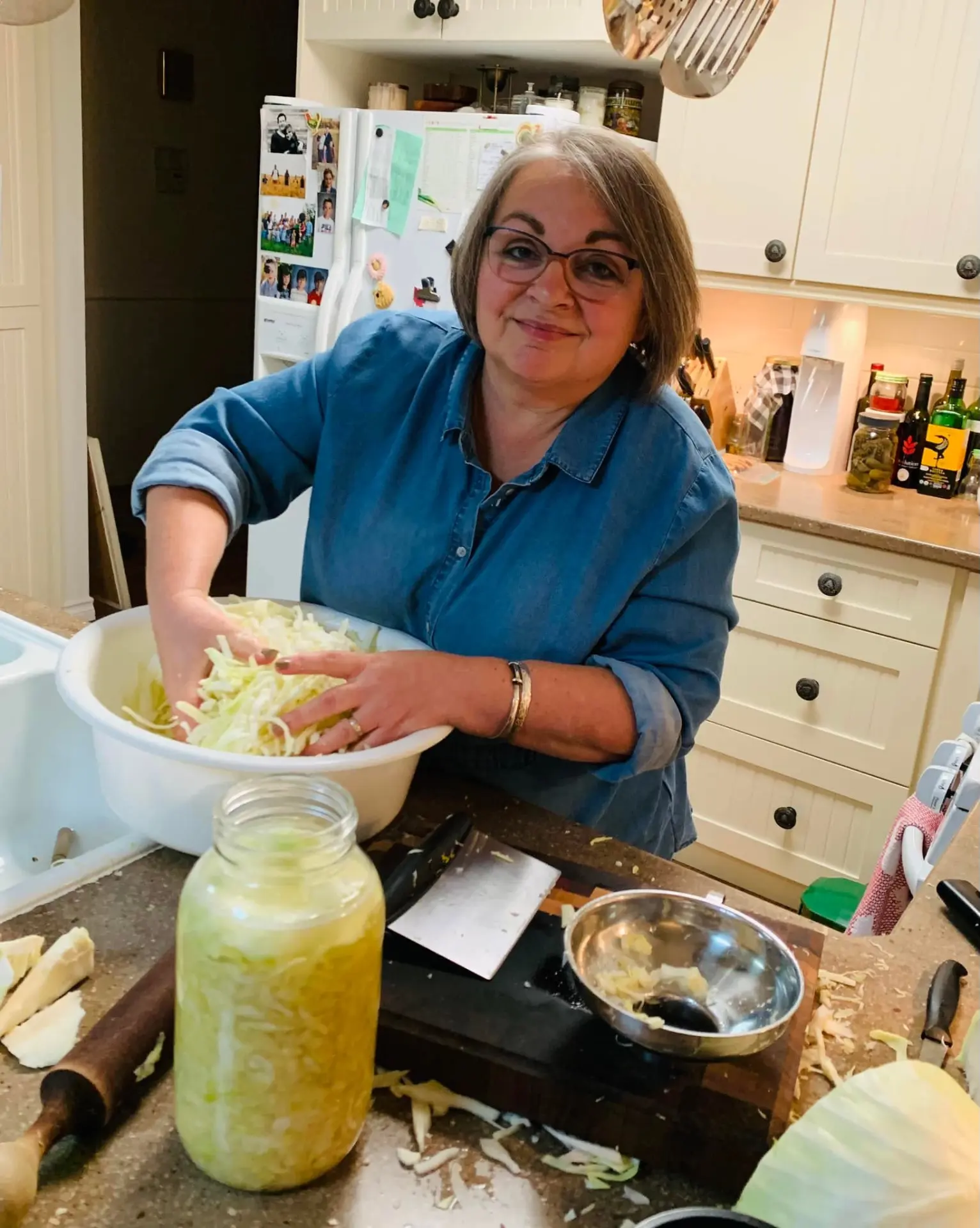 Cindy packing shredded cabbage into a jar to make sauerkraut in her kitchen